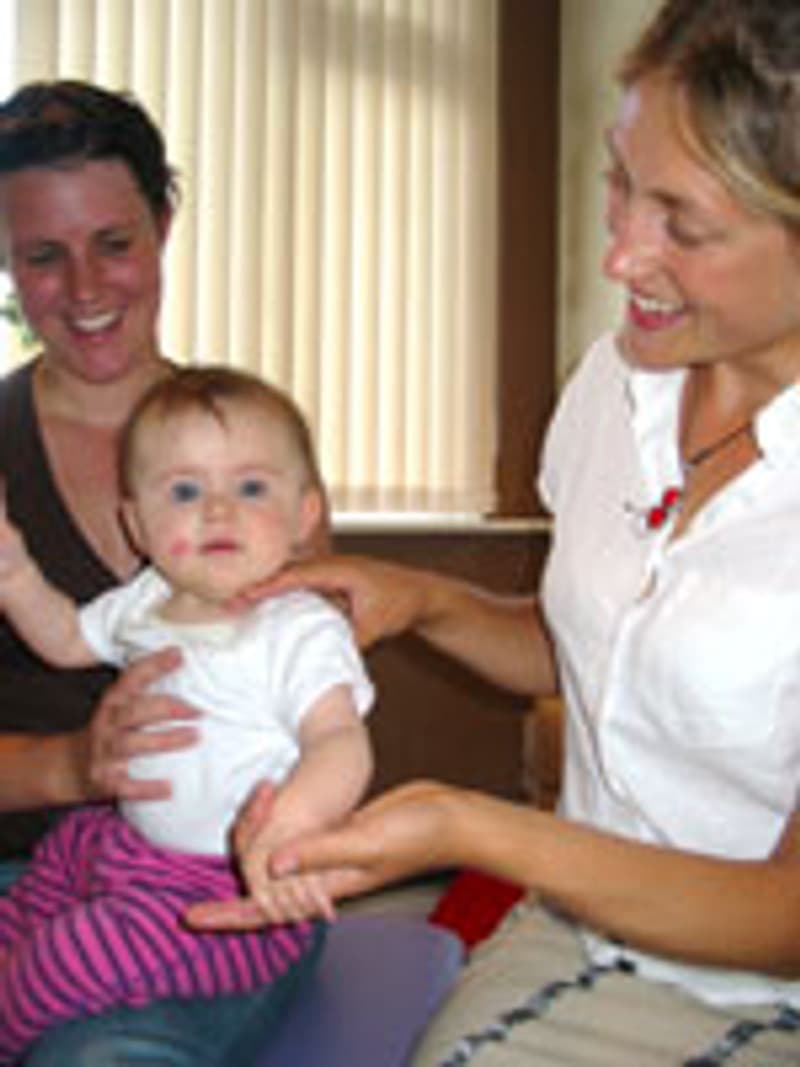 Rachael Dunn gently supporting a baby's torso while a parent holds them — paediatric care at Vibrant Life