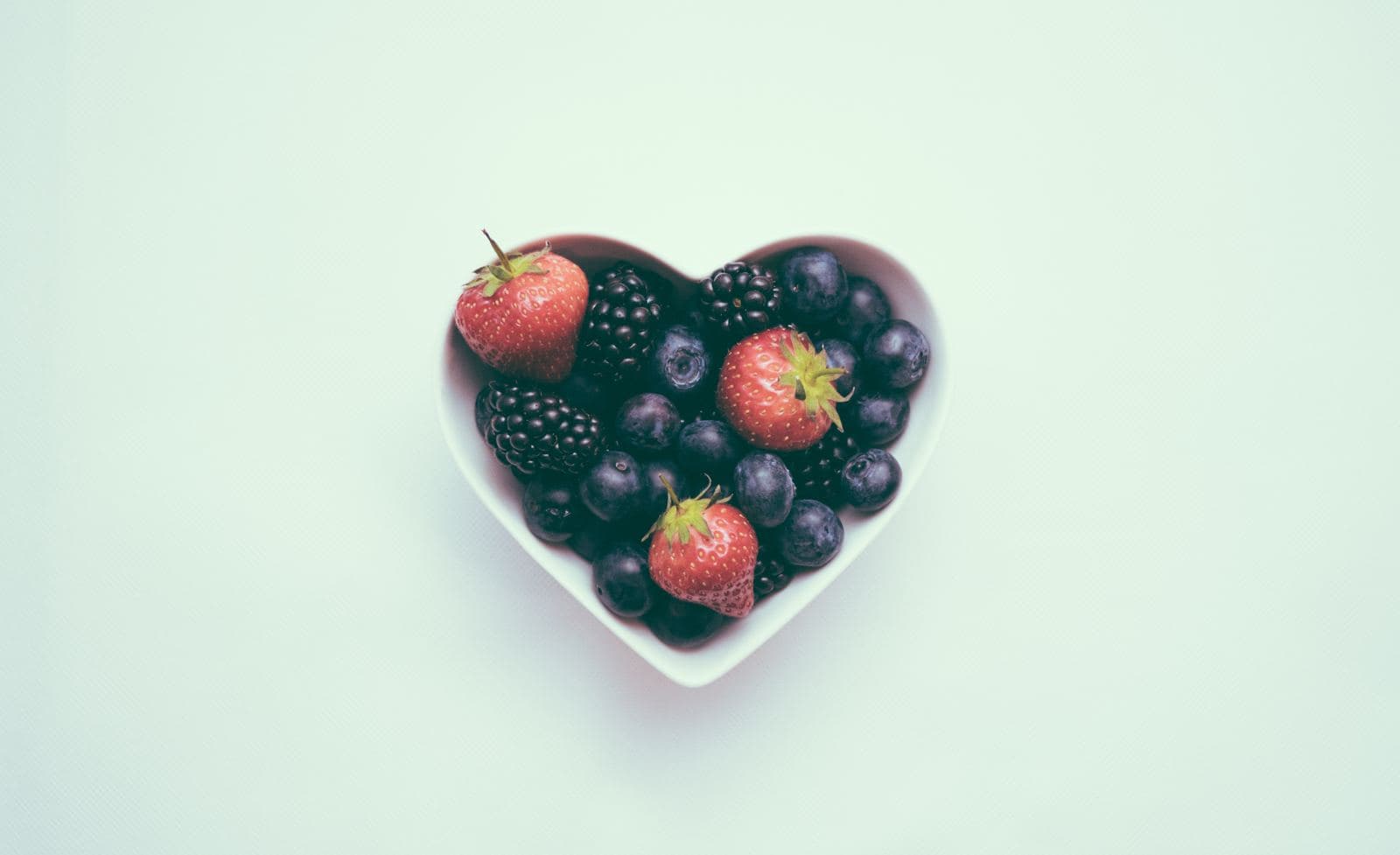 Heart-shaped bowl of fresh strawberries, blackberries and blueberries